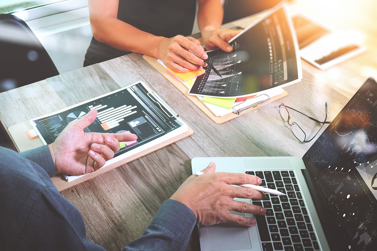 Two people looking at laptop and data documents