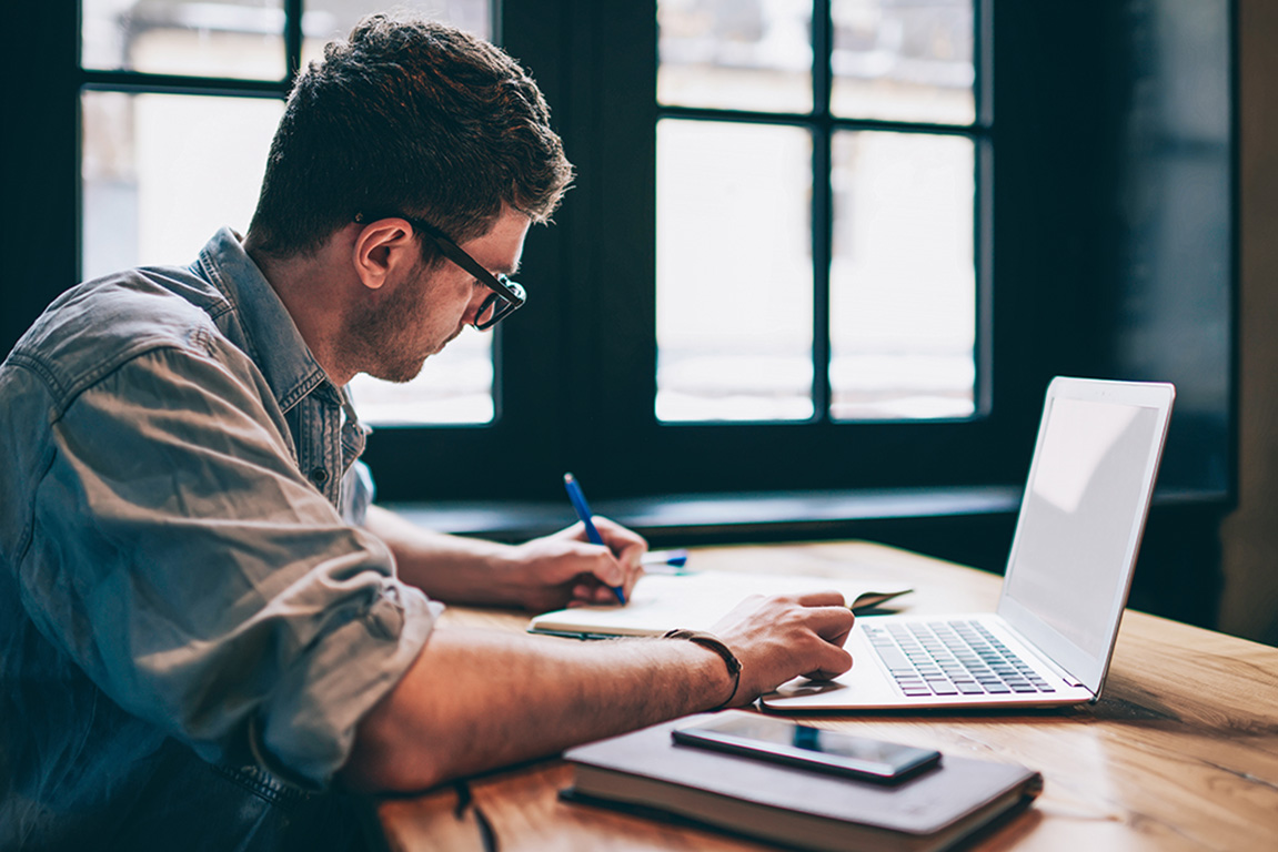 Man studying with laptop and notebook