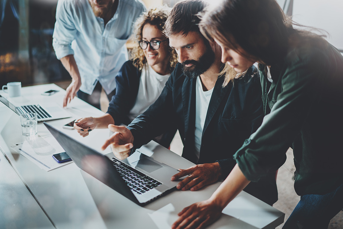 Man and two women looking at laptop